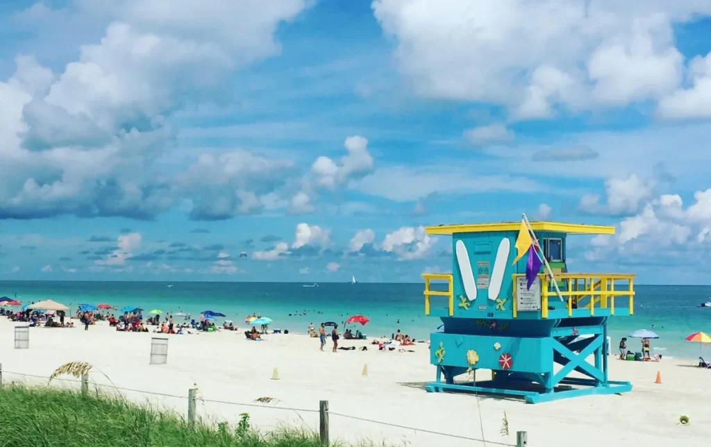 Praia de South Beach em Miami com turistas aproveitando o sol e guarda-sóis coloridos
